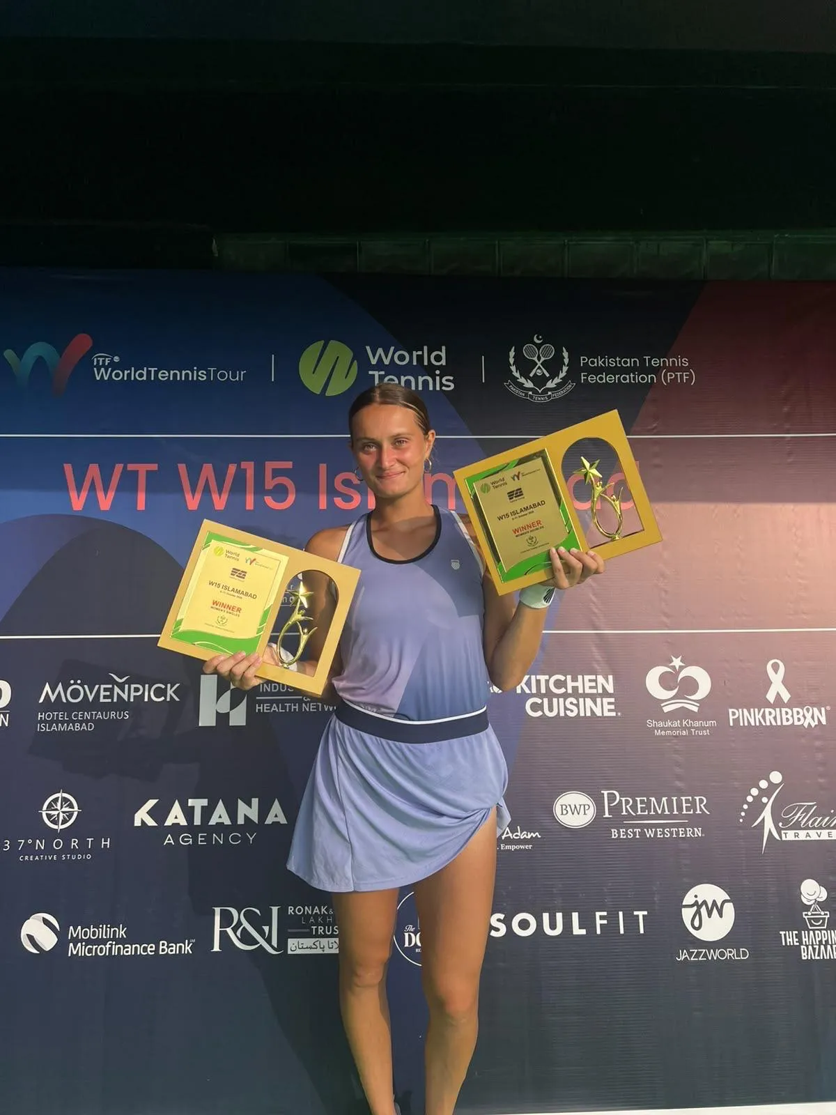 Astrid Cirotte sourit, un trophée de vainqueure du W15 d'Islamabad dans chaque main