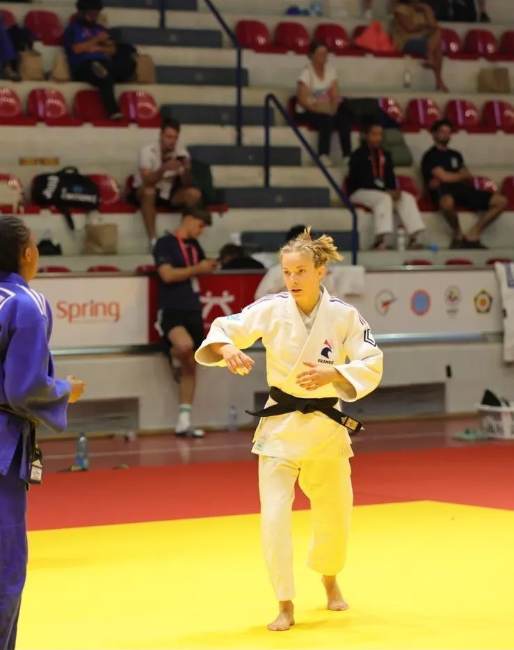 Clara Mermet, en kimono blanc et ceinture noire, se place face à son adversaire sur le tatami