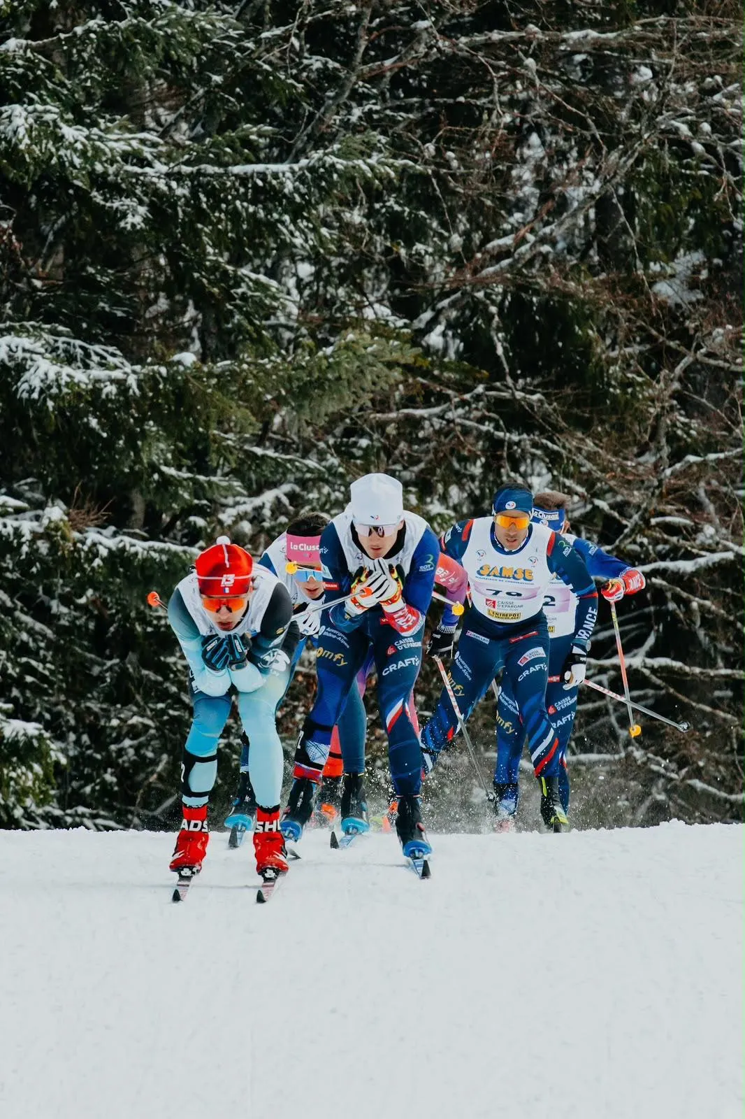 Noa Genest, bonnet rouge, mène un groupe de fondeurs de l'équipe de France dans une montée enneigée