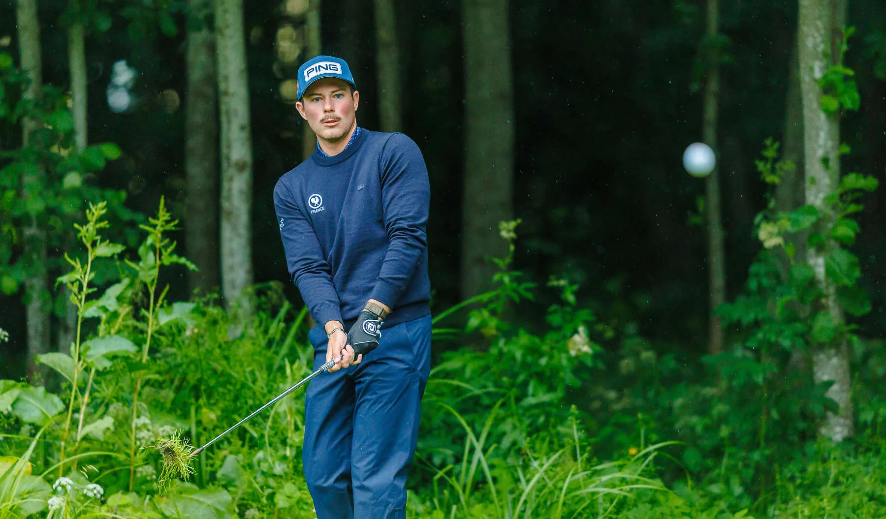 Paul Beauvy, pull de l'équipe de France, suit des yeux sa balle après un coup joué depuis les hautes herbes, en lisière de forêt