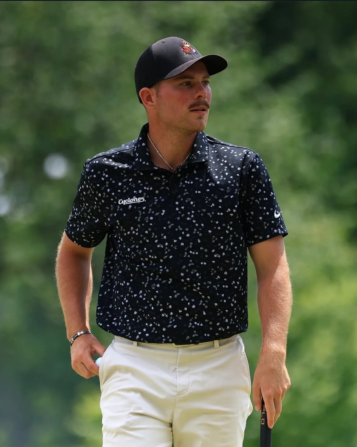 Paul Beauvy, casquette noire et polo à fleurs, marche sur le parcours, putter à la main
