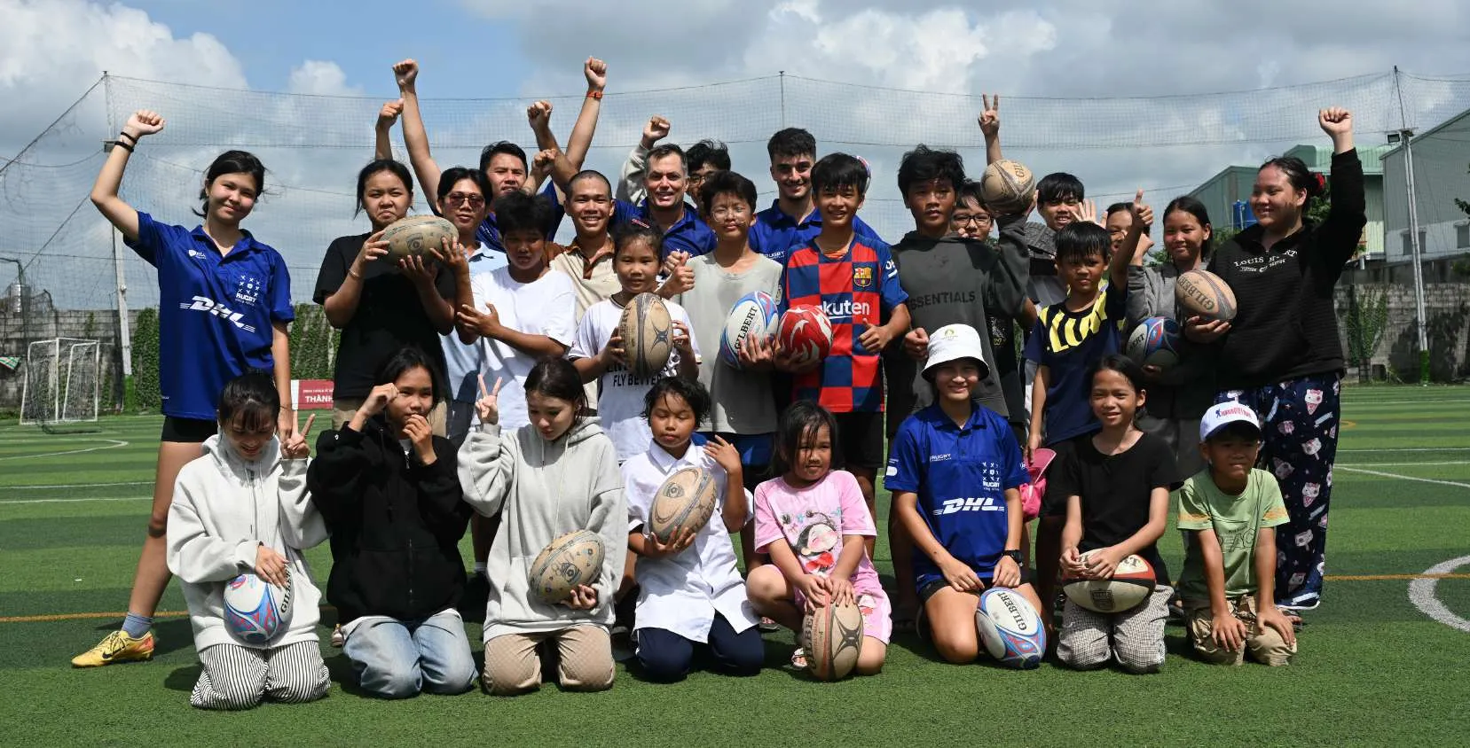 Des enfants et leurs coachs posent, ballons de rugby en main, à la fin d'une séance à Hoc Mon