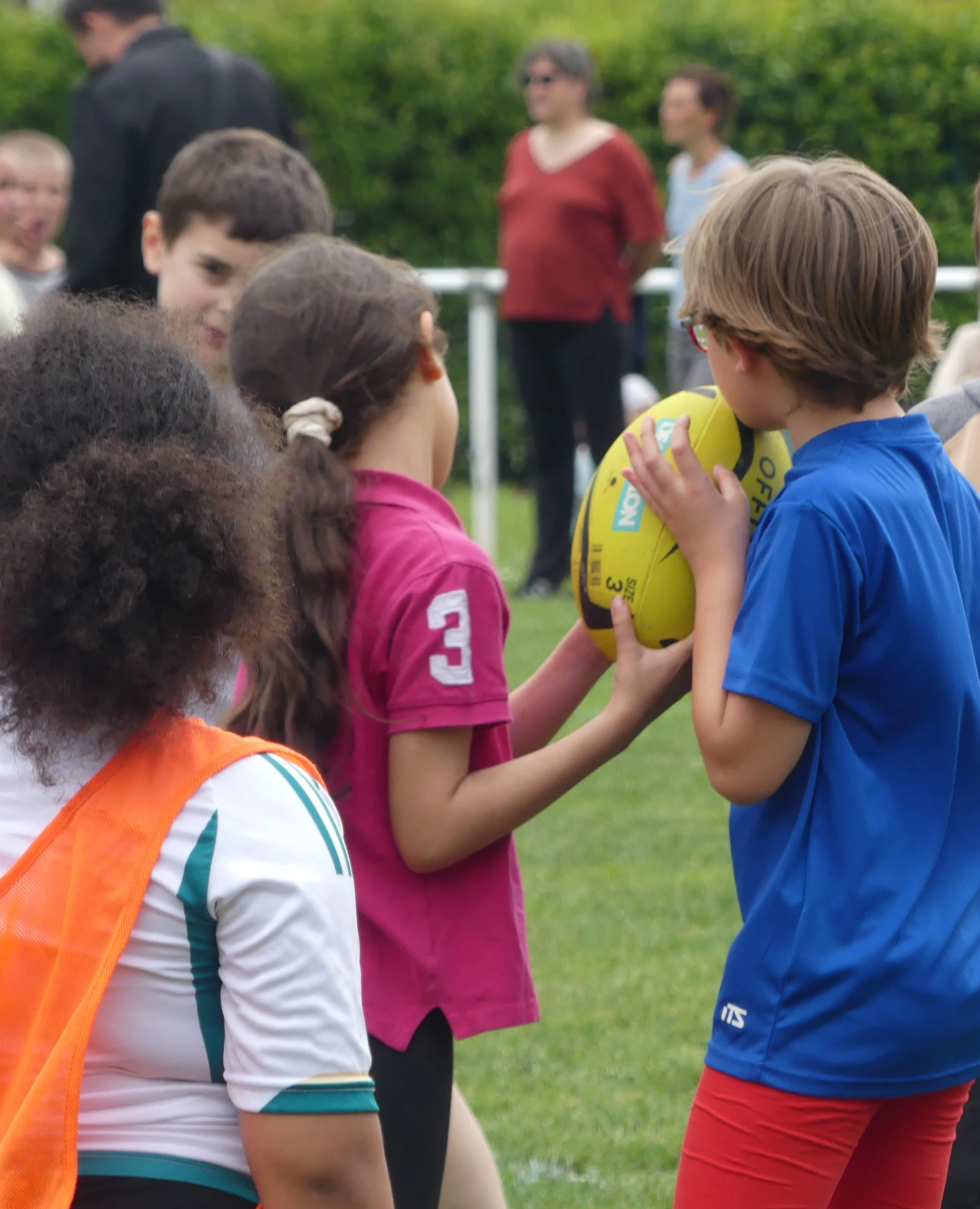 Des enfants se passent un ballon de rugby jaune lors d'une séance éducative